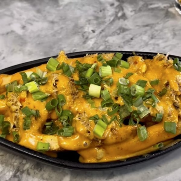 TNT Rooftop Restaurant's fries covered in melted cheese, shredded meat, and chopped green onions.