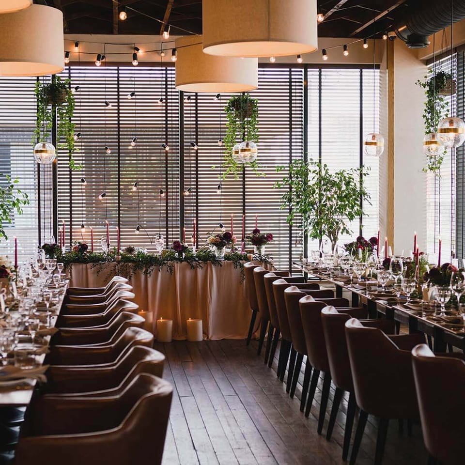 A long dining table set for a formal event at TNT Rooftop Restaurant, with candles and greenery.