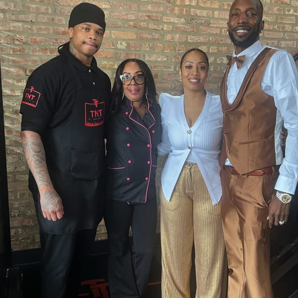Four TNT Rooftop Restaurant staff members, two men and two women, stand smiling against a brick wall.