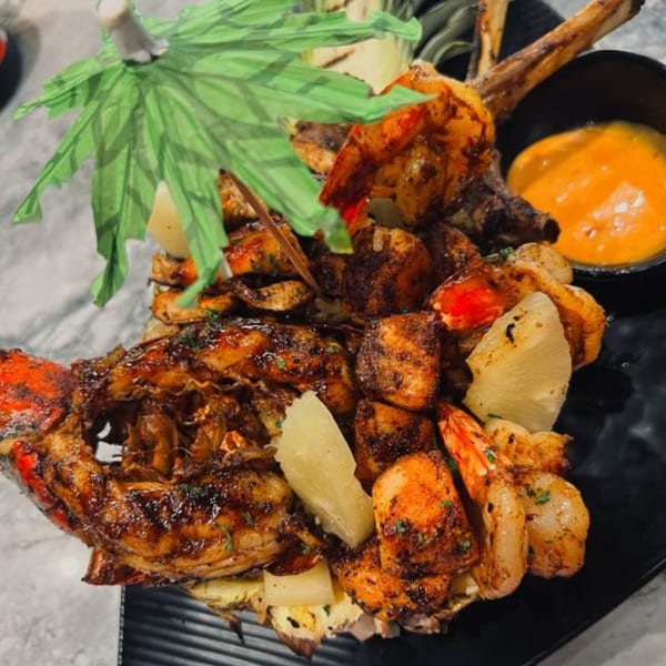 Grilled lobster, shrimp, and pineapple chunks served with a dipping sauce at TNT Rooftop Restaurant.