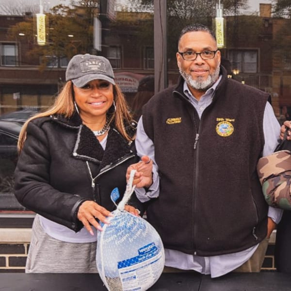 Two people, a woman and a man, standing outside holding a frozen turkey.
