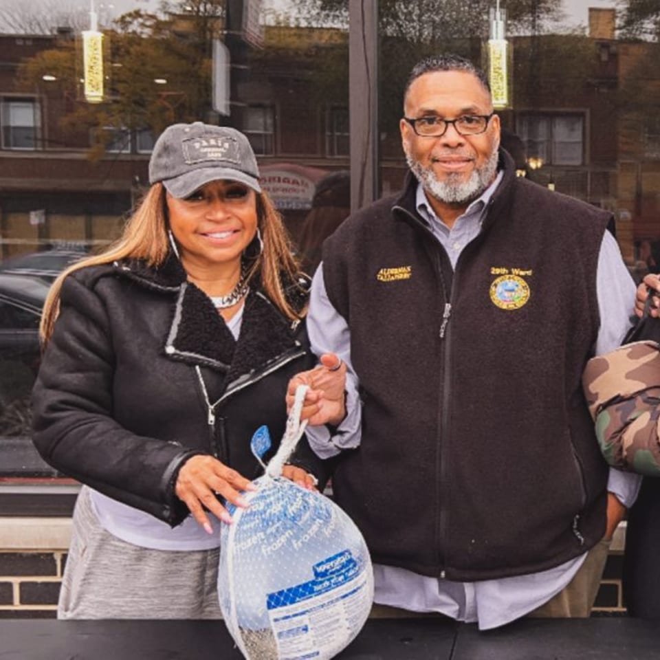 Two people, a woman and a man, standing outside holding a frozen turkey.
